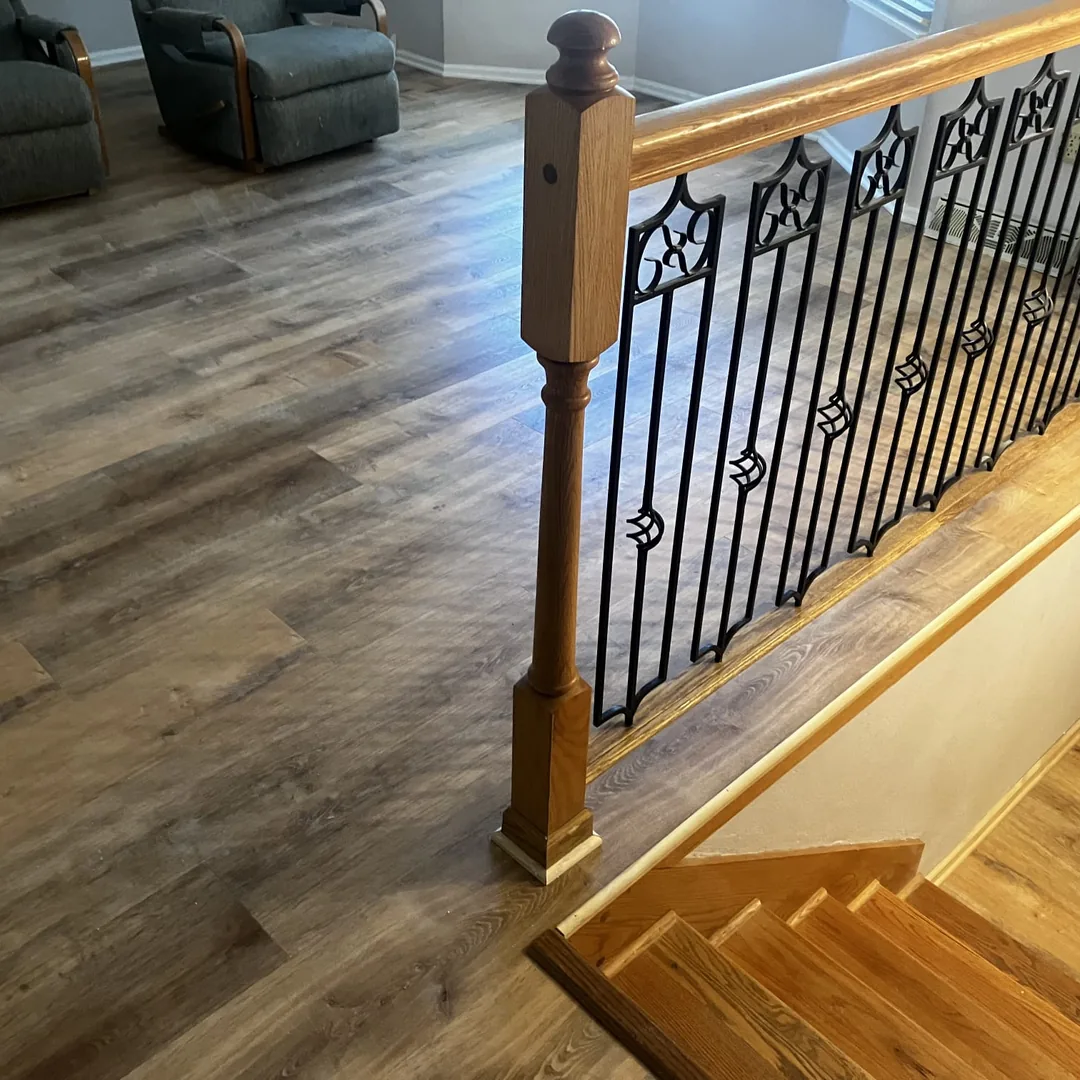 Finished basement stairway with wrought iron railing and luxury vinyl plank flooring by MrImproveIt