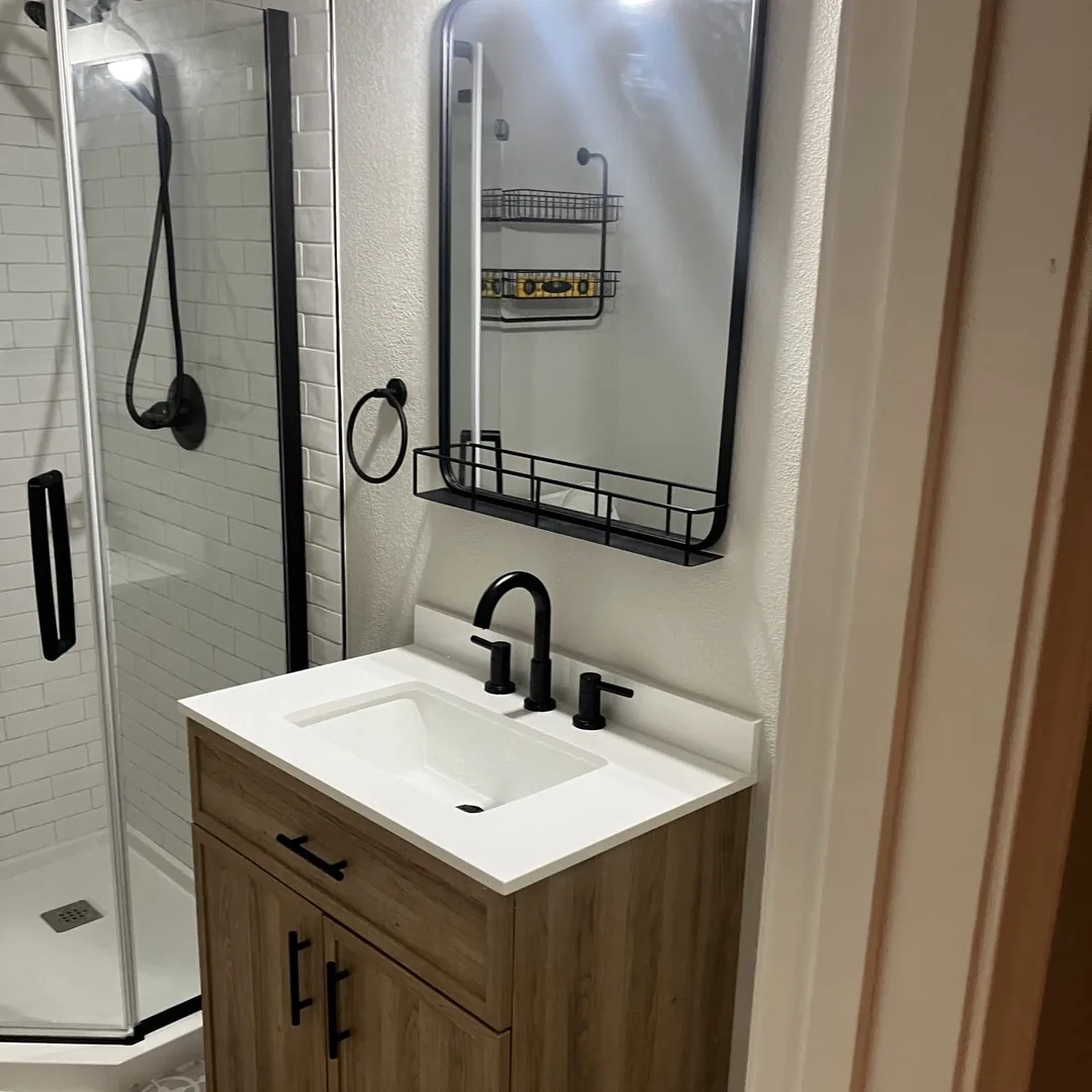 Bathroom remodel with wood vanity, black fixtures and glass shower door by MrImproveIt